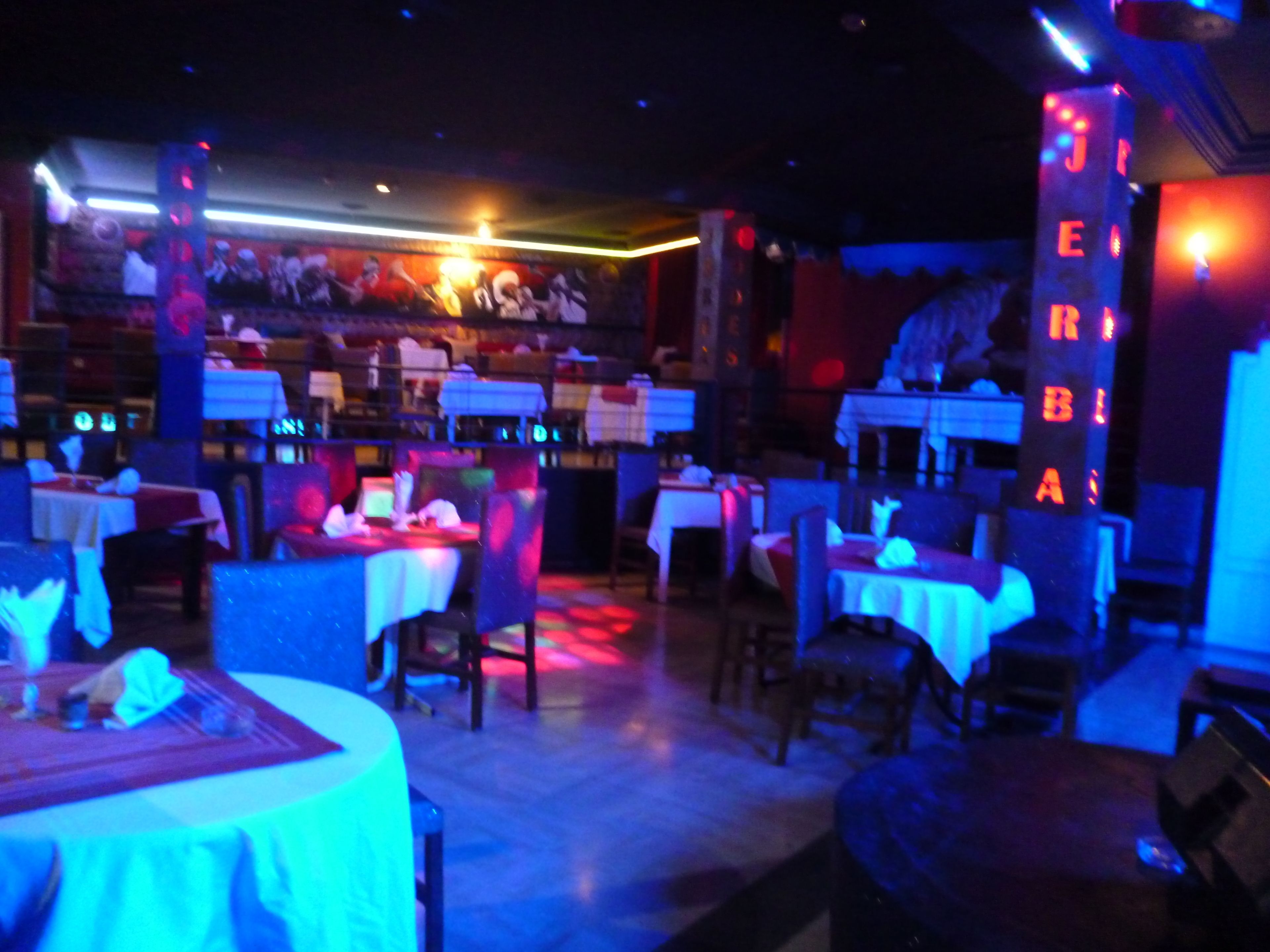 Ein Restaurant in gedämpfter Beleuchtung, mit Tischen und Stühlen für die Gäste.