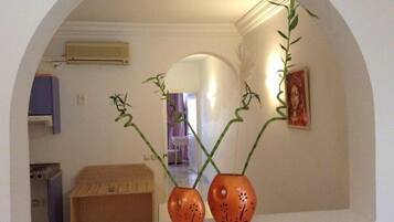 A room with an arched mirror reflecting two orange vases with green plants.
