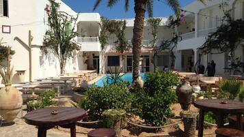 Un patio con piscina, mobiliario exterior y una palmera.