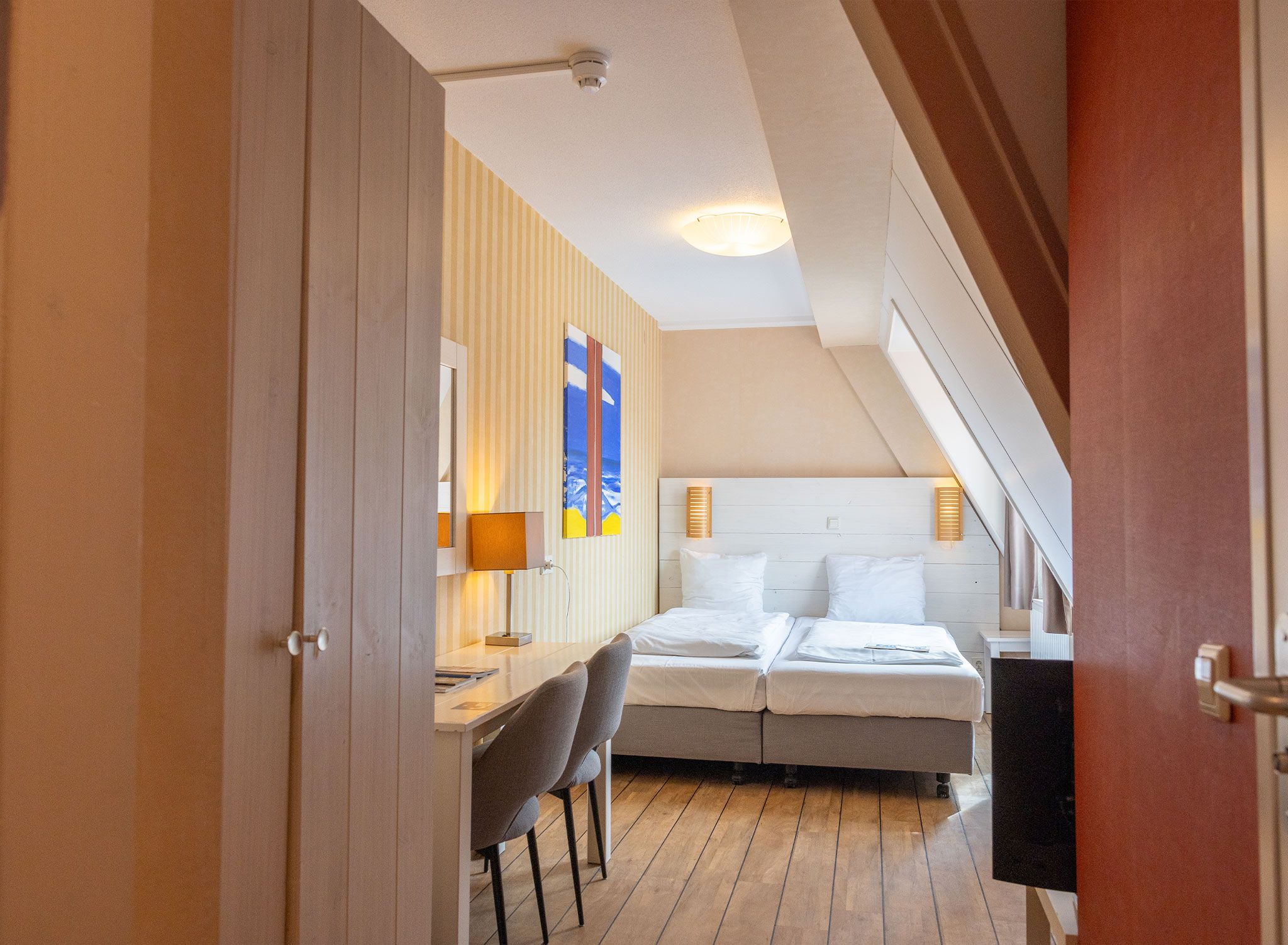 A hotel room with a bed, a desk with a chair, and a TV.