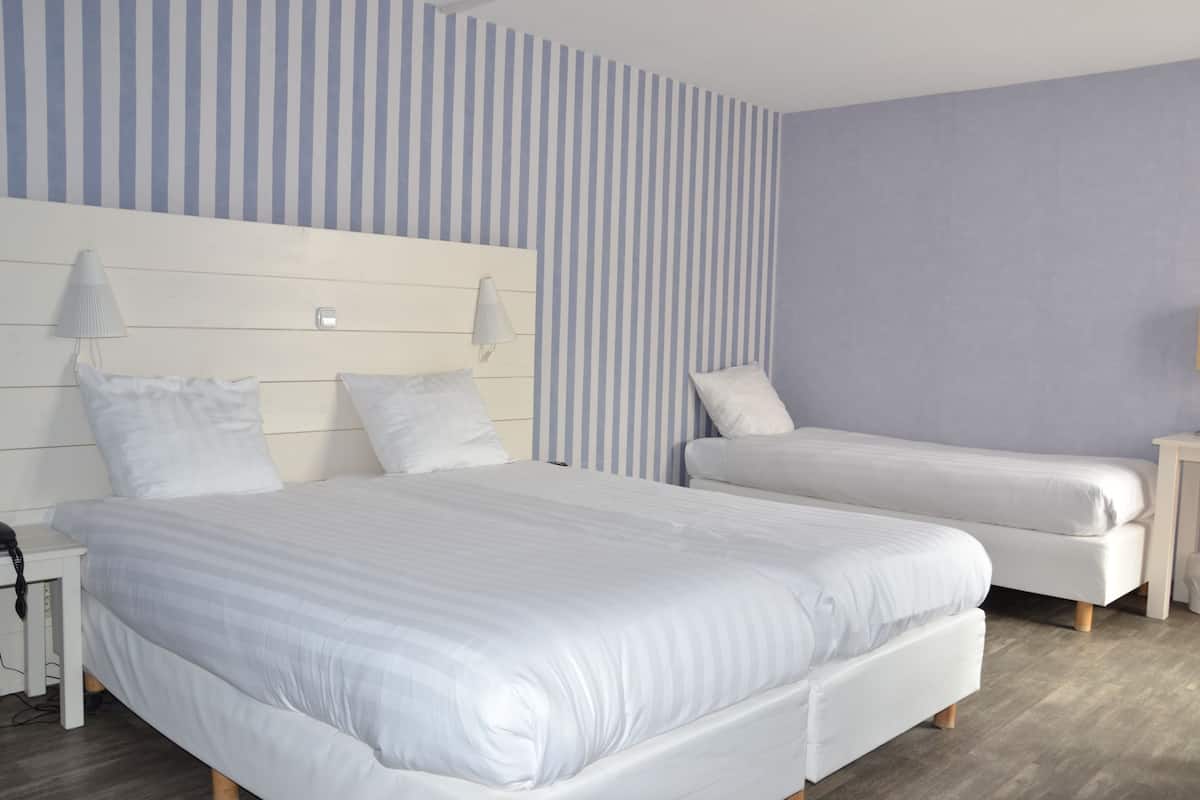 Une chambre d’hôtel avec deux lits, une table de chevet, une lampe et un mur à rayures.