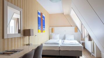 Ein Hotelzimmer mit Bett, Schreibtisch, Stuhl, Lampe und Fenster.