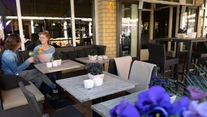Un espace extérieur aménagé avec des tables et des chaises, des plantes en pot et une vue sur la rue.