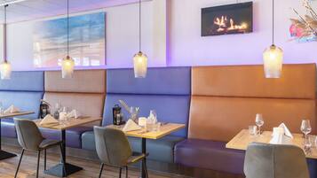 A restaurant interior with booths, tables, and hanging pendant lights.
