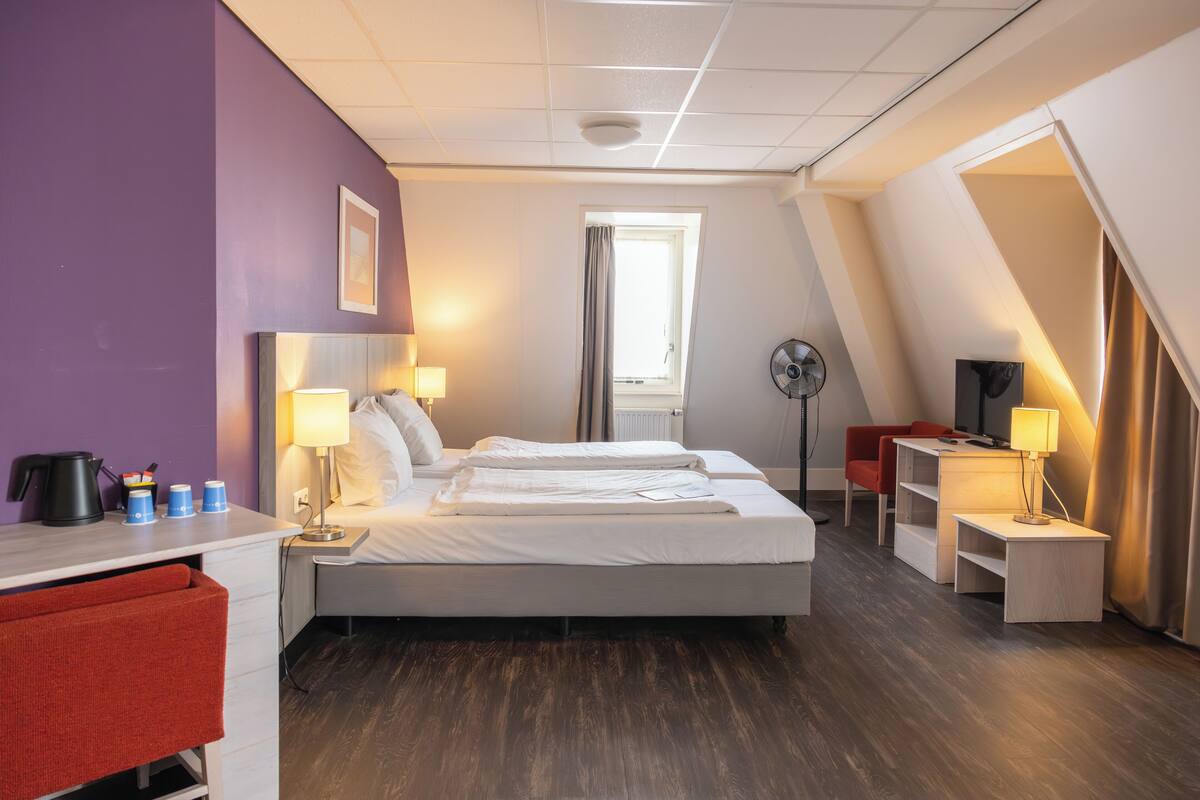 Une chambre d’hôtel moderne équipée d’un lit, de tables de chevet, d’un bureau, d’une chaise et d’une fenêtre.