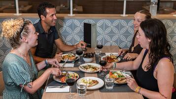 A group of people dining at a restaurant with a modern interior, including patterned wall tiles and wooden tables.