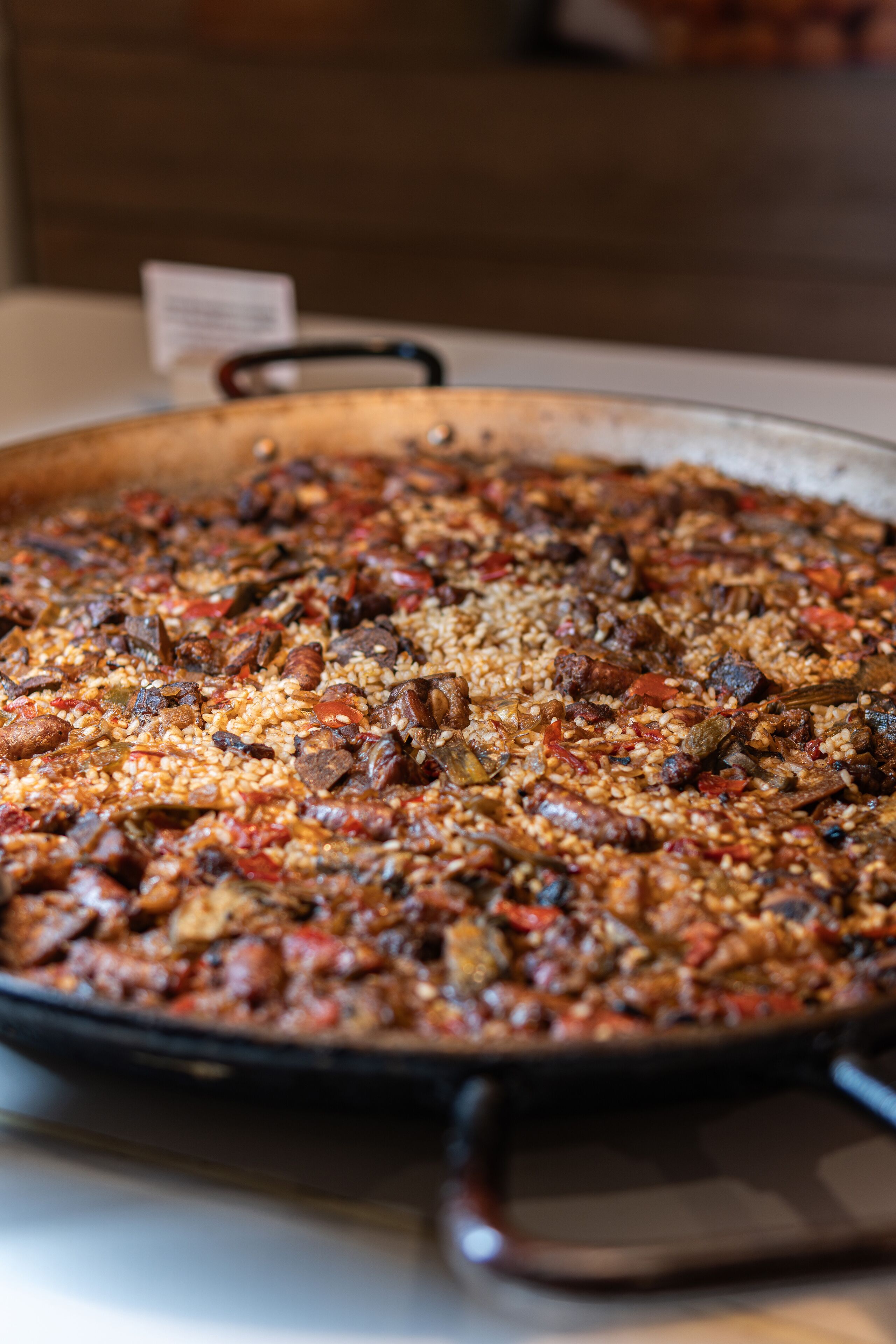 Une grande poêle peu profonde, remplie d’un plat composé de riz, de viande et de légumes.