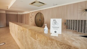 A reception desk with a marble top, a hand sanitizer dispenser, and a sign recommending hydroalcoholic gel. - Checkin Blanes (Blanes)