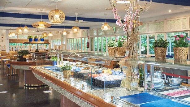 A buffet area with a variety of food items, wicker baskets, and potted plants. - Checkin Blanes (Blanes)