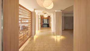 A modern hallway with a wooden partition, a light-colored floor, and pendant lighting. - Checkin Blanes (Blanes)