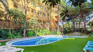 A swimming pool with a surrounding grassy area and lounge chairs. - Checkin Blanes (Blanes)