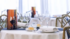 Una mesa de comedor dispuesta con copas de vino, platos y una carta.