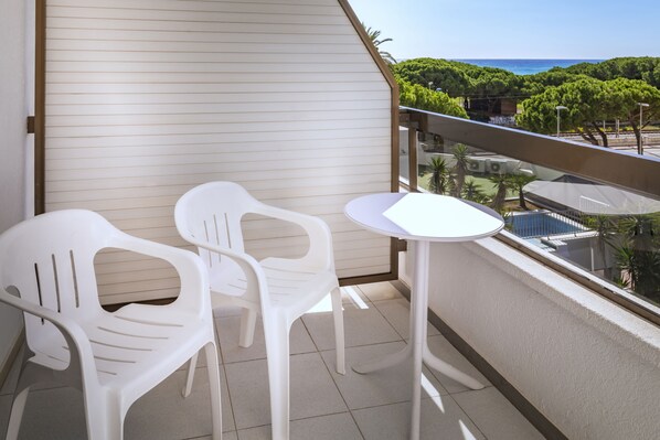 A balcony with two white plastic chairs and a small white table.