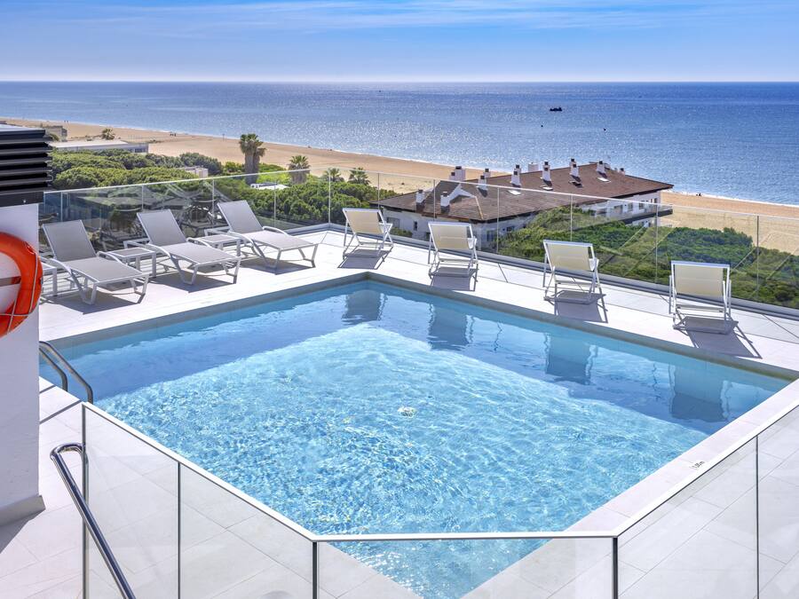A rooftop infinity pool with a clear view of the beach and ocean.