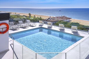 Una piscina infinita en la azotea con vistas despejadas a la playa y al océano.