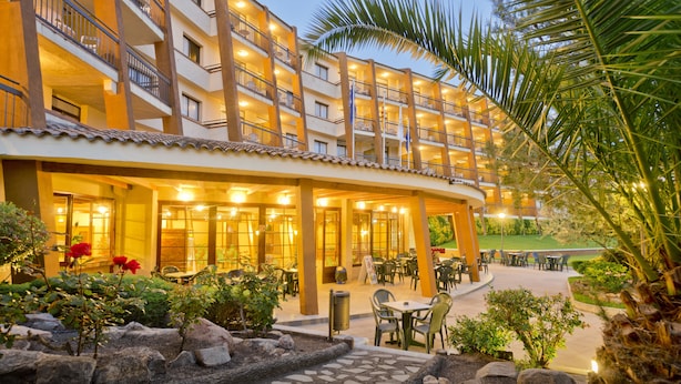 A hotel with multiple balconies, outdoor seating, and a landscaped garden area. - Apart-hotel GHT Tossa Park (Tossa de Mar)