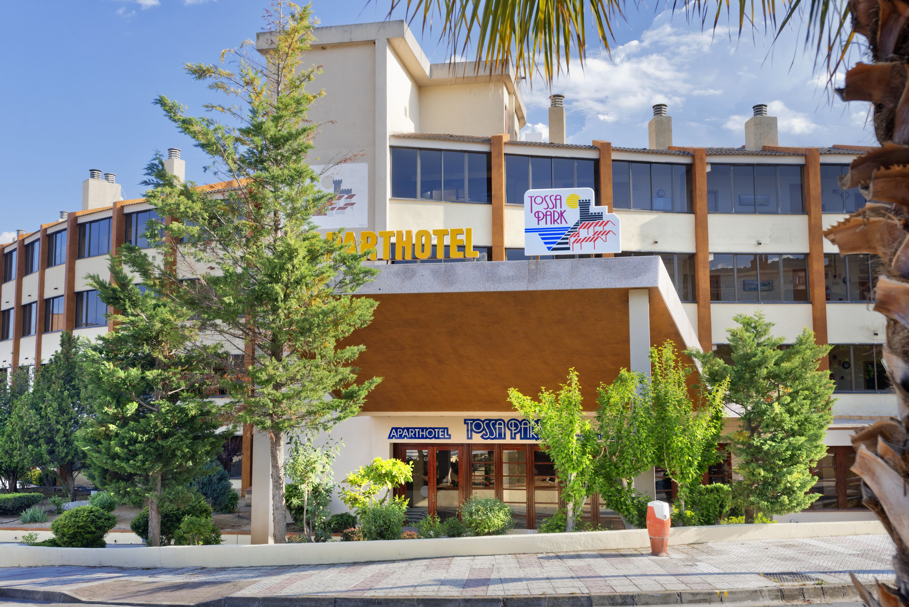 A modern building with signs for 'Toss Park' and 'Apartment Hotel'.