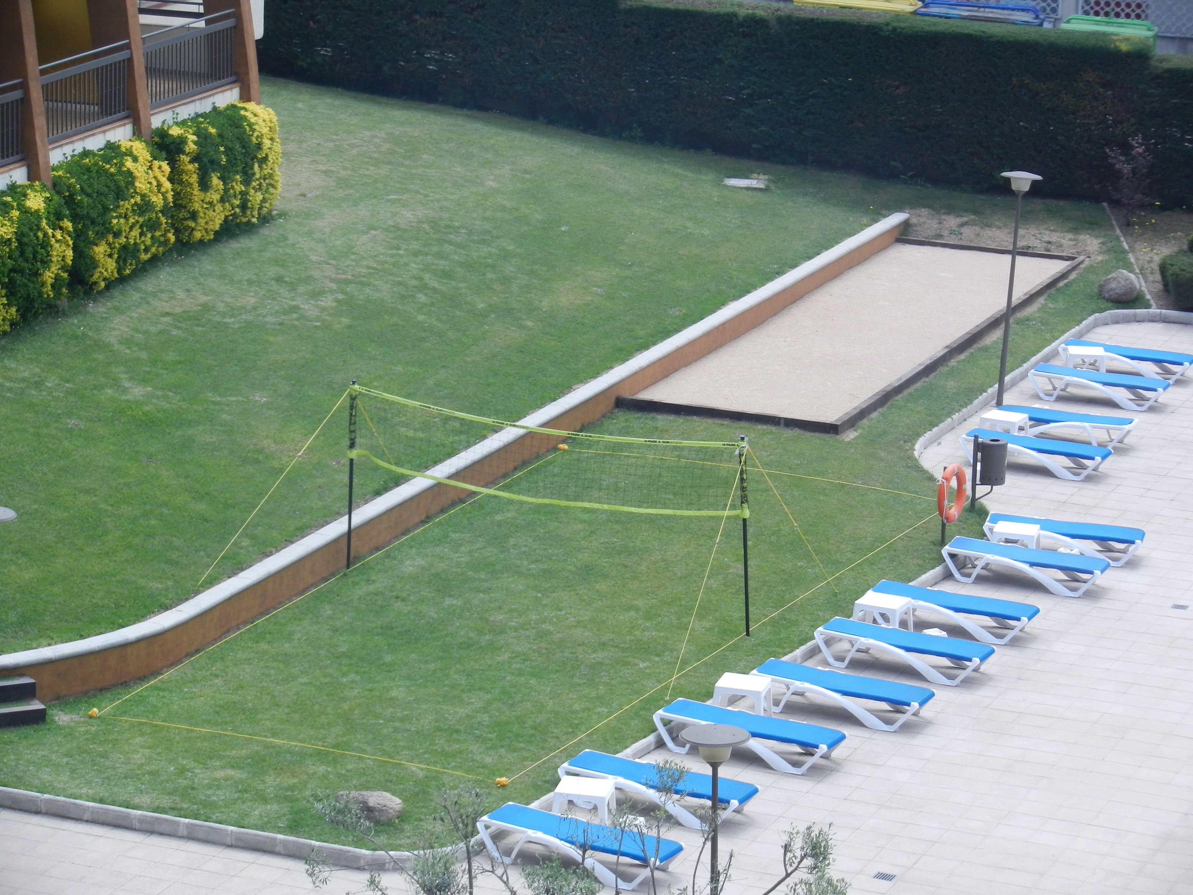 Un área de piscina con sillas reclinables azules y blancas dispuestas en filas, una piscina pequeña y un flotador cerca del borde.