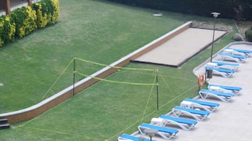 Un área de piscina con sillas reclinables azules y blancas dispuestas en filas, una piscina pequeña y un flotador cerca del borde.