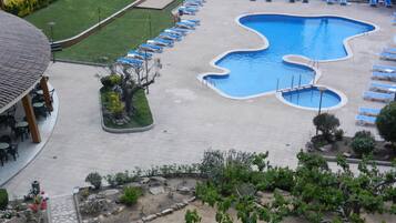 A swimming pool with multiple lanes, surrounded by lounge chairs and a covered seating area.