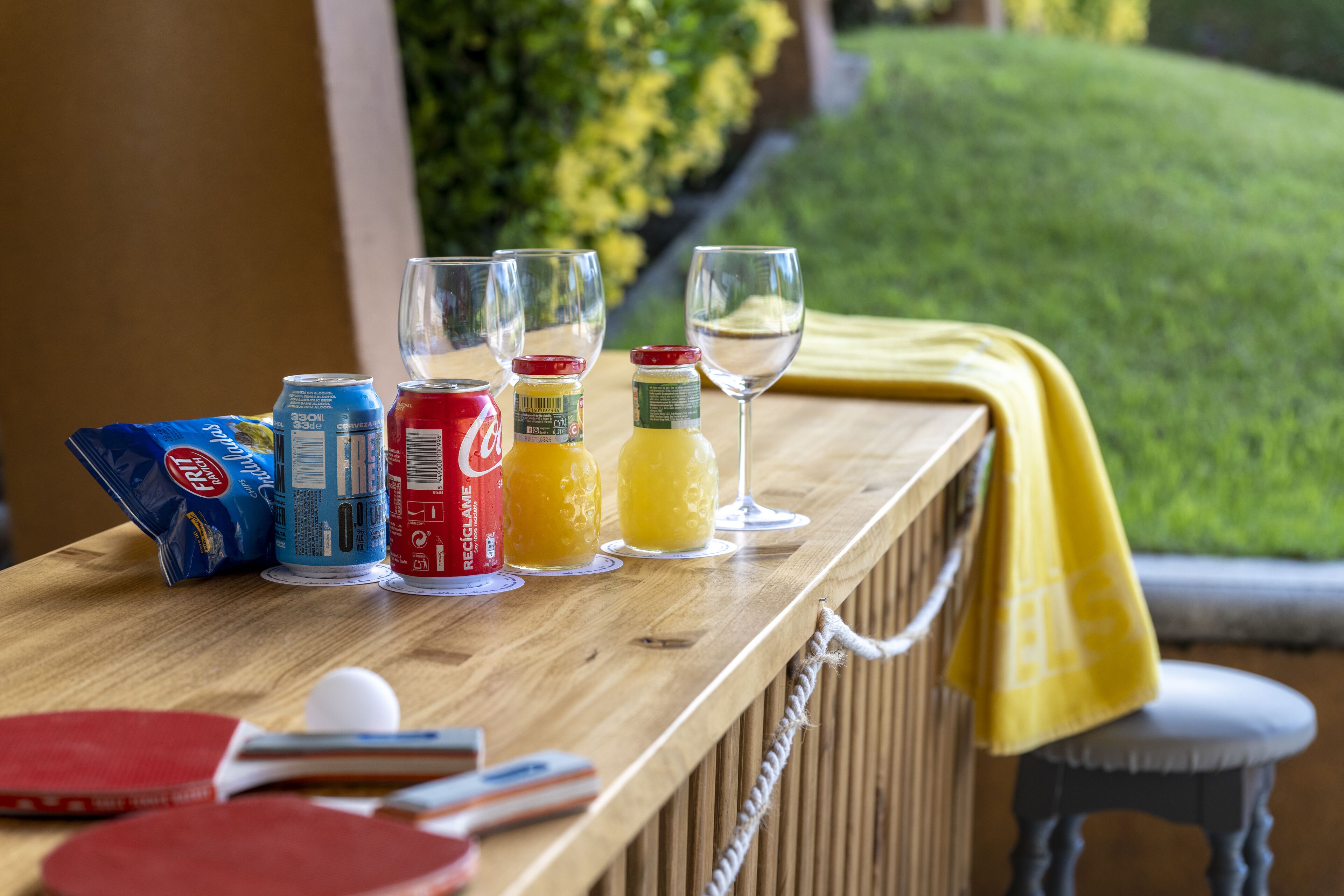 A wooden bar counter with various beverages and a ping pong table.