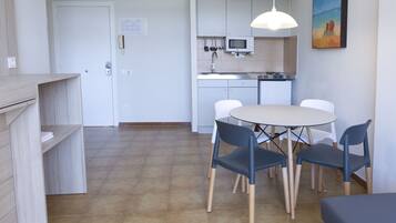 A compact kitchen with a microwave, sink, and dining area with chairs and a table.