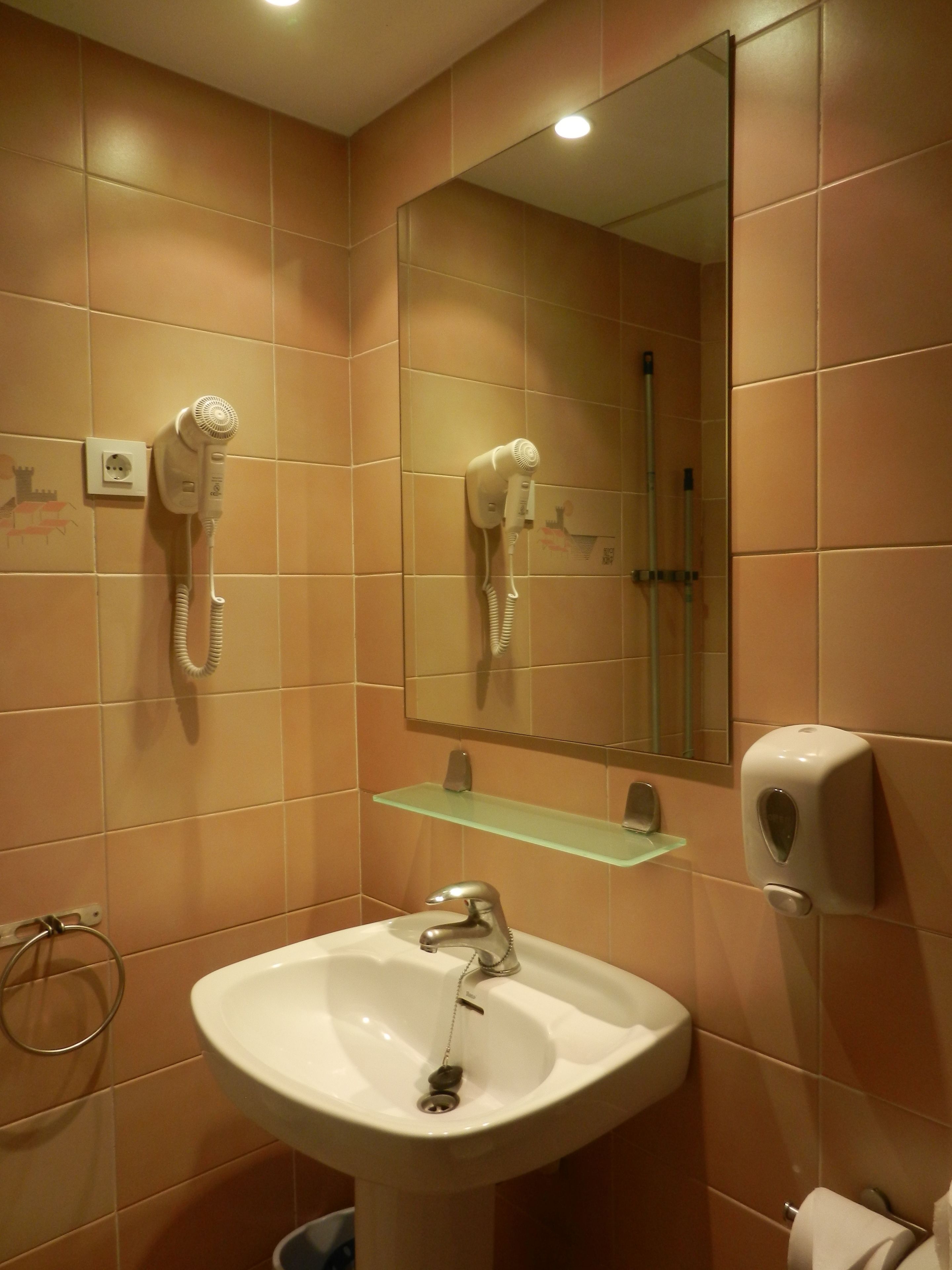 A bathroom with a sink, mirror, hairdryer, and towel rack.