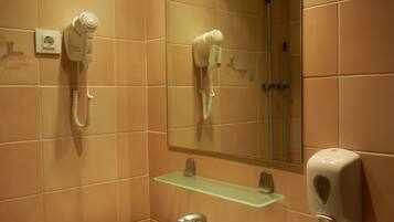 A bathroom with a sink, mirror, hairdryer, and towel rack.