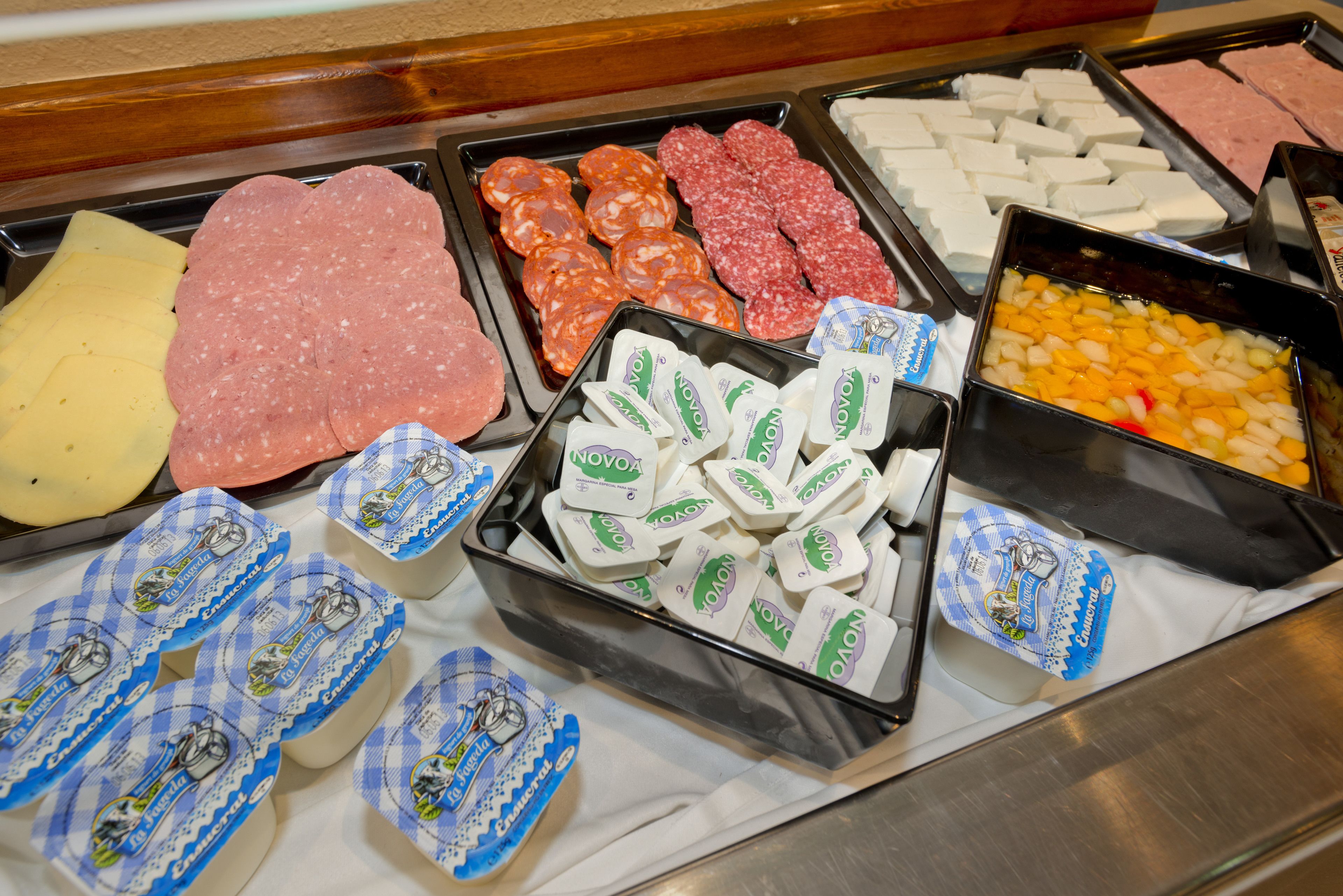 A deli counter with various meats, cheeses, and packaged dairy products.
