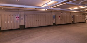 A row of lockers with a 'No Parking Anytime' sign, a 'No Smoking' sign, and a 'No Entry' sign on the wall.