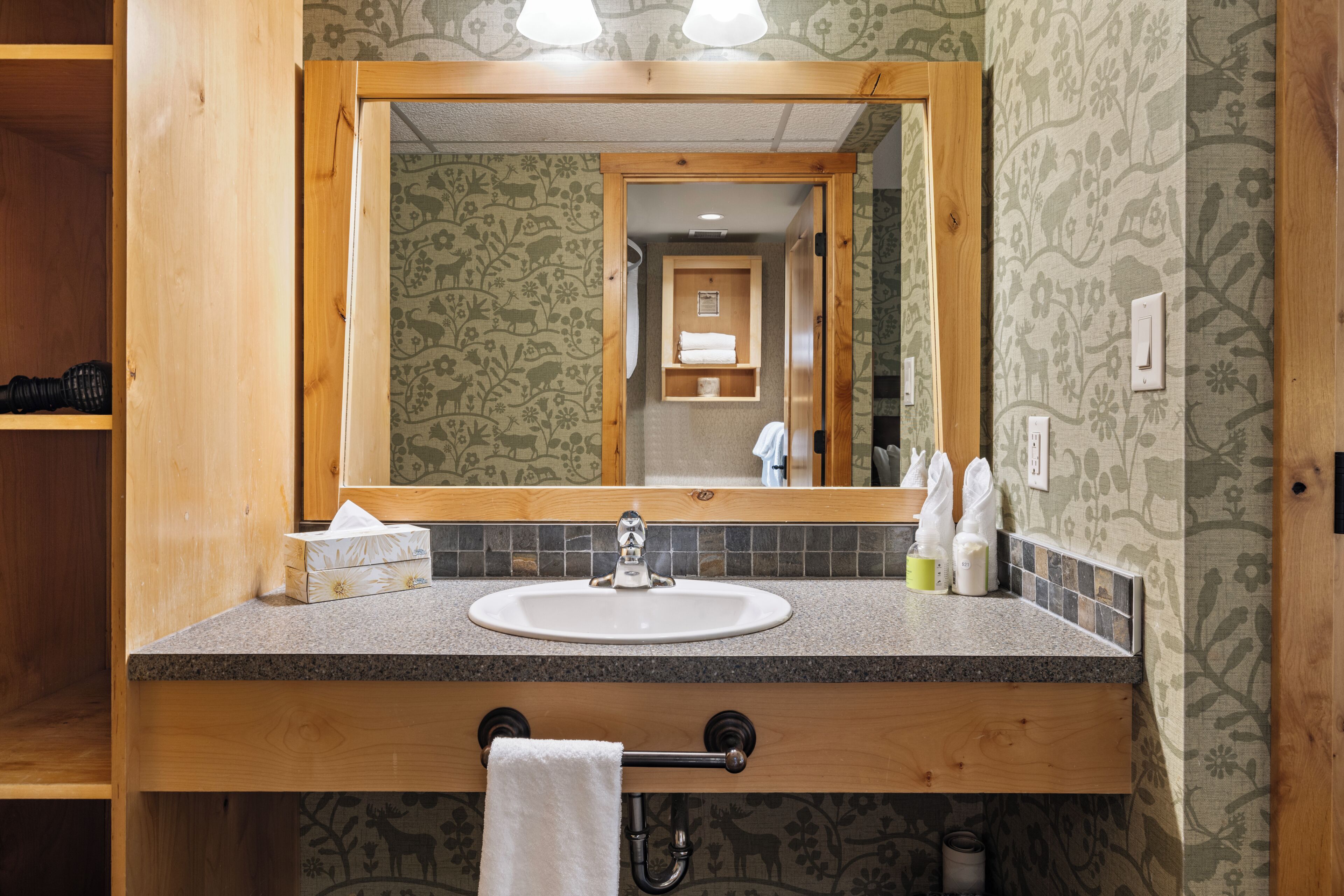 A bathroom with a wooden vanity, a sink, a mirror, and a towel rack.