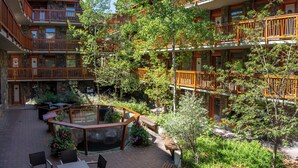 A multi-story building with balconies, outdoor seating, and a small pond. - The Fox Hotel and Suites (Banff)