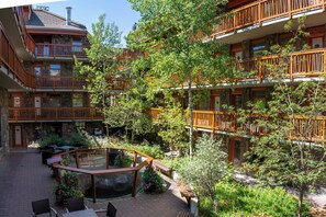 A multi-story building with balconies, outdoor seating, and a small pond.