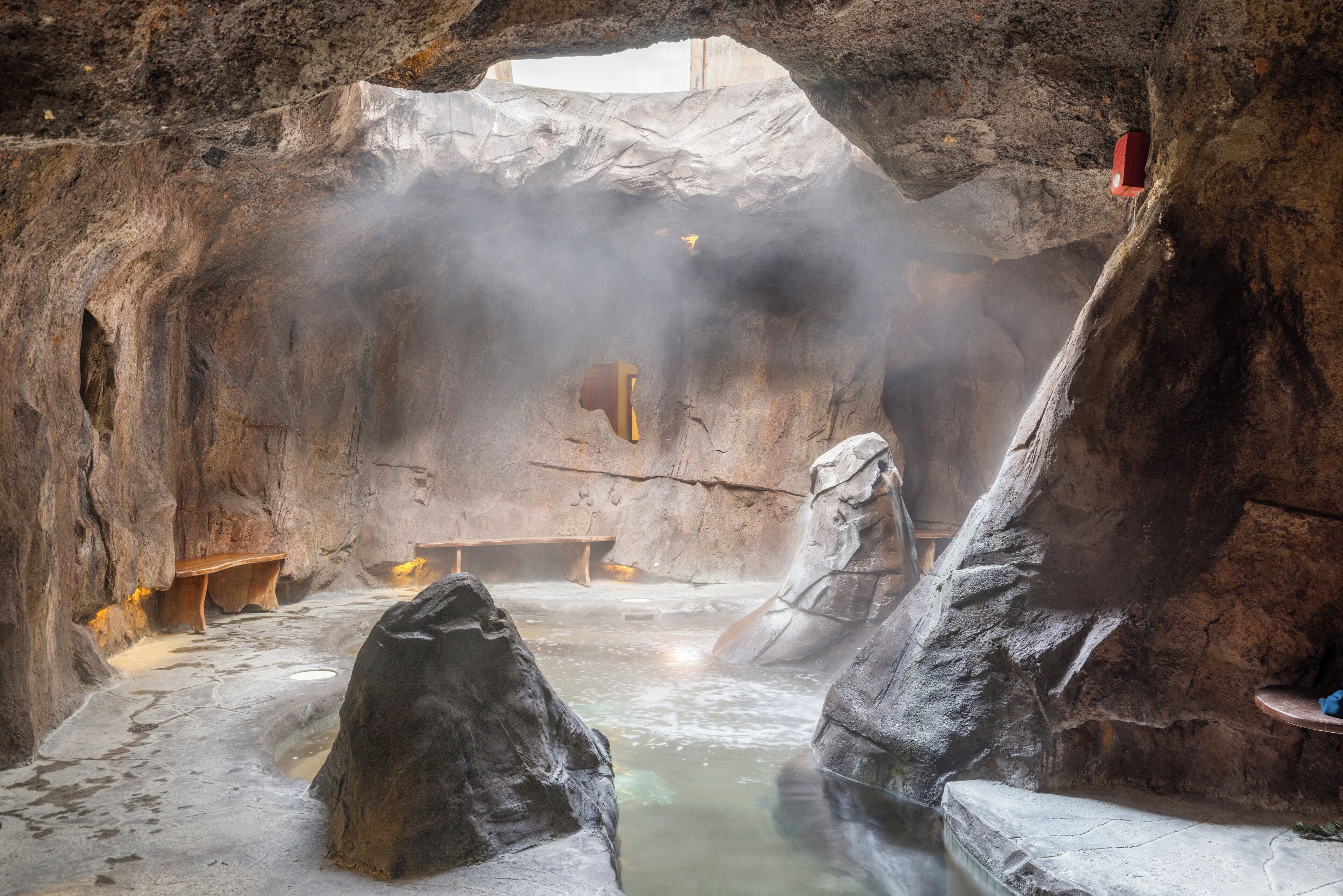 An indoor hot spring area with benches and a wooden structure.