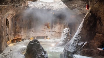 Un área de aguas termales interior con bancos y una estructura de madera.