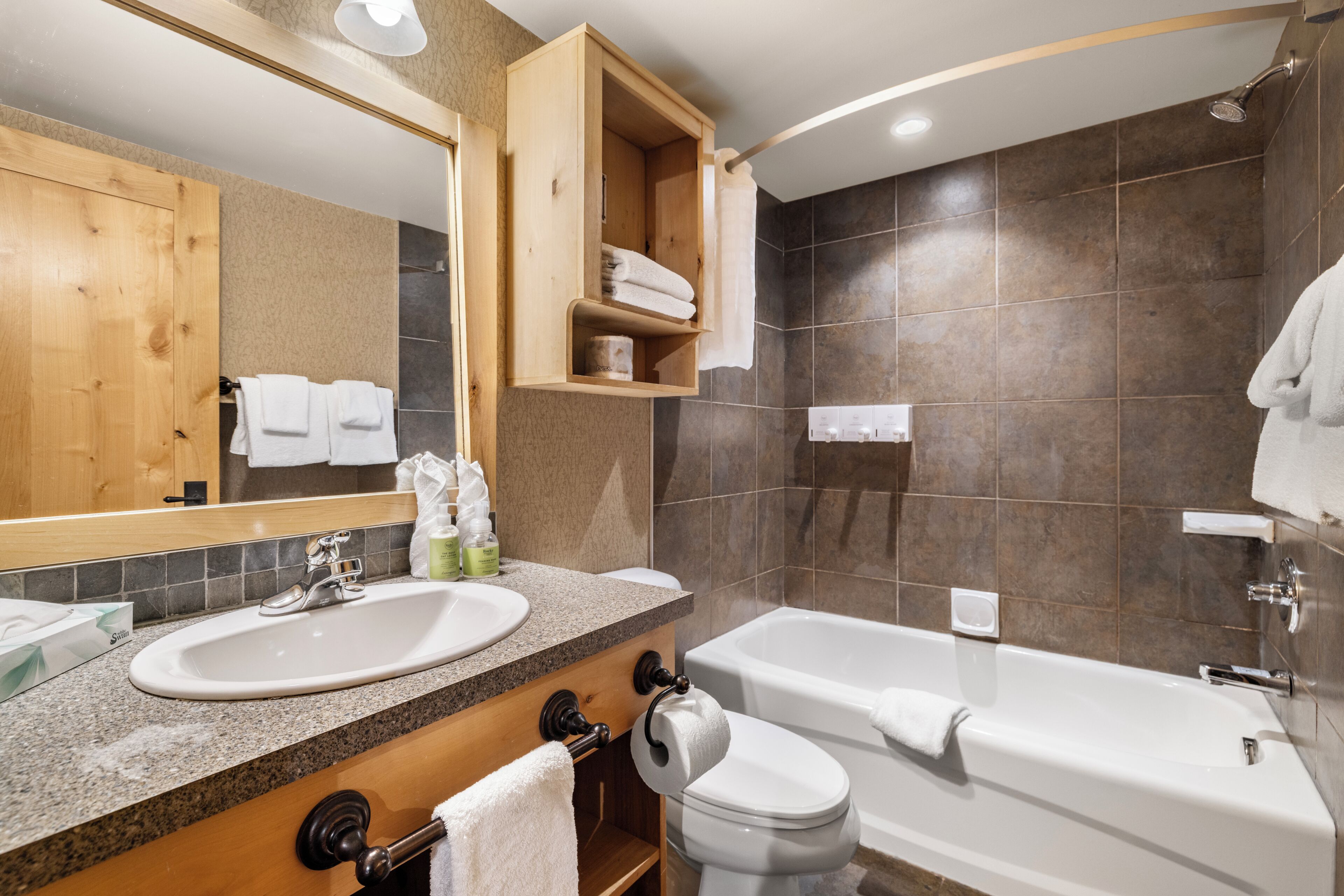 A modern bathroom with a large mirror, two sinks, a toilet, and a bathtub.