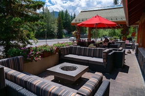 Relax by the fire pit in a cozy seating area surrounded by lush greenery and a wooden pergola.