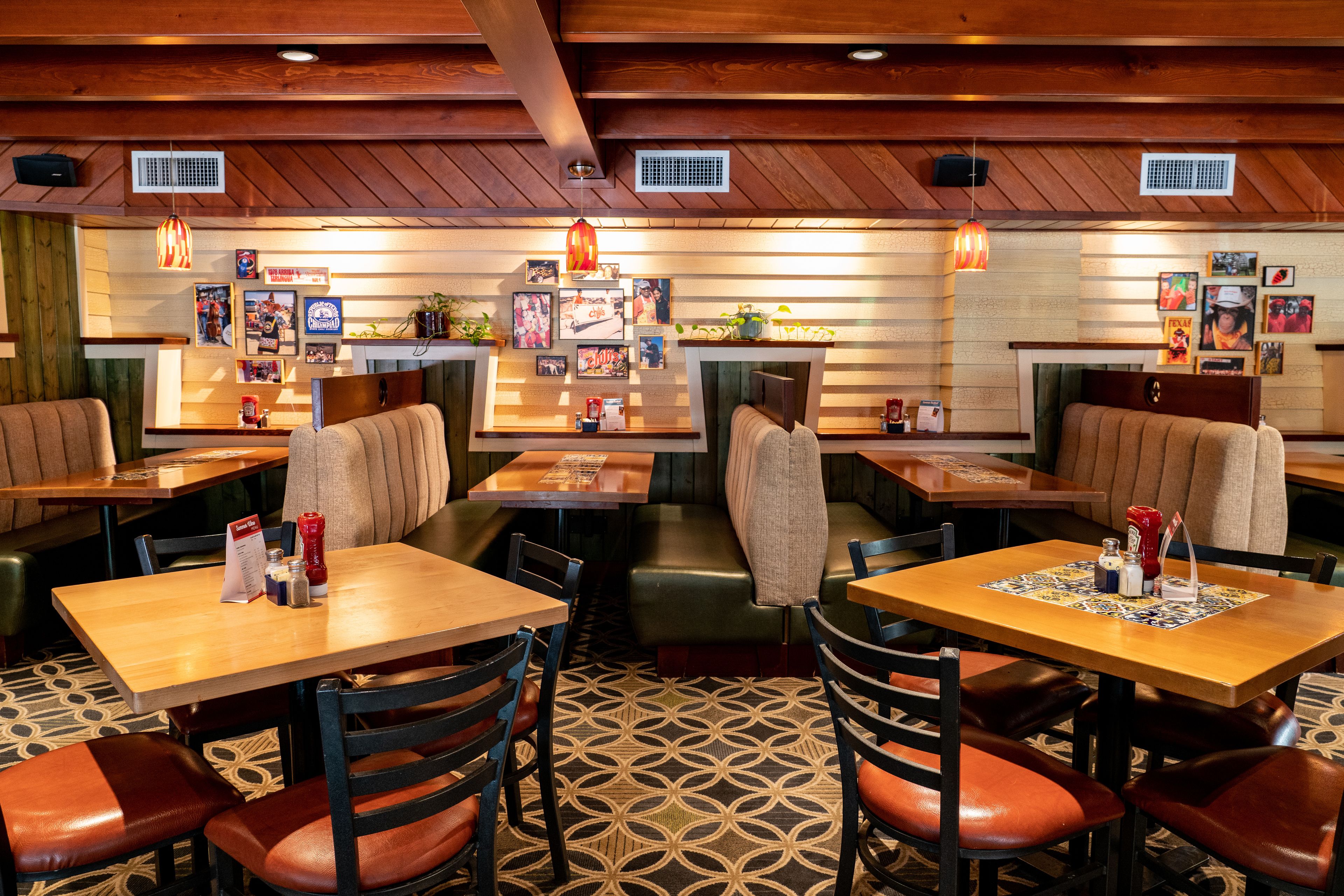 Un restaurant avec des banquettes et des tables, un plafond en bois et des tableaux accrochés aux murs.