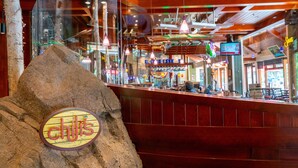 L’intérieur d’un restaurant, avec un bar en bois, des cloisons en verre et des suspensions lumineuses.