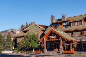 A lodge with a prominent 'FOX' sign, stone exterior, and a mountain backdrop. - The Fox Hotel and Suites (Banff)