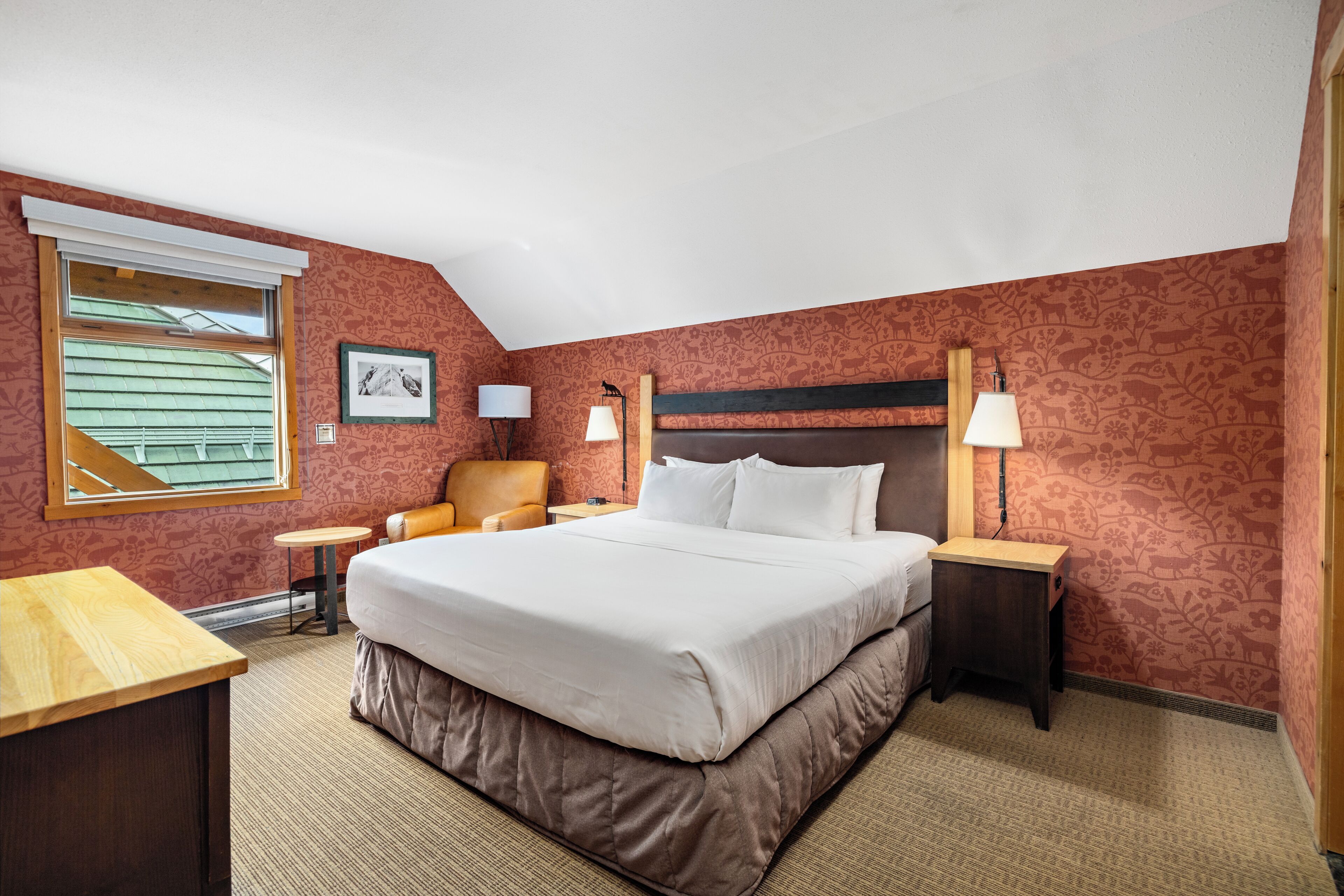 Une chambre d’hôtel avec un grand lit, une chaise, une table et une lampe.