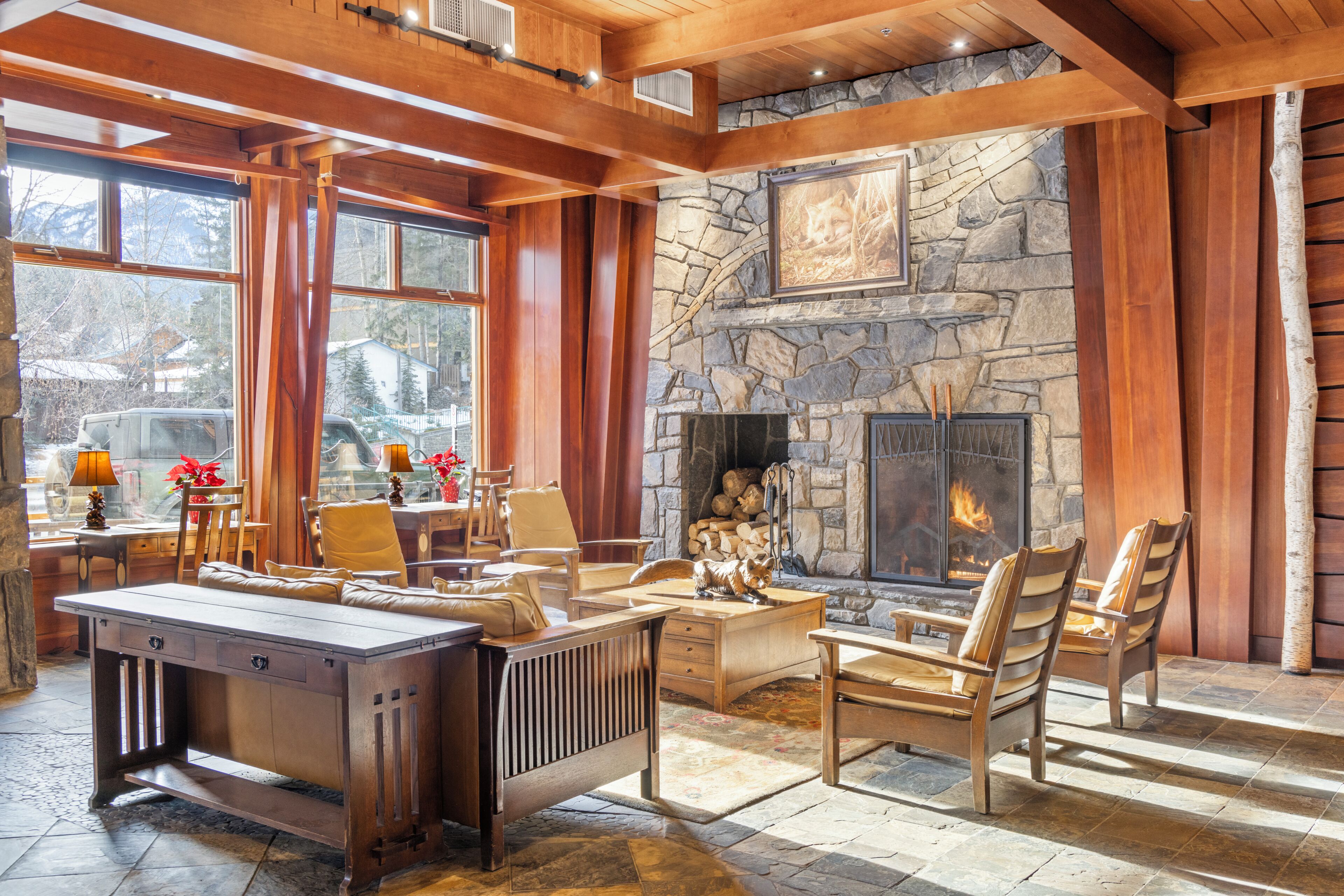 Un interior acogedor con chimenea de piedra, muebles de madera y vistas al exterior.
