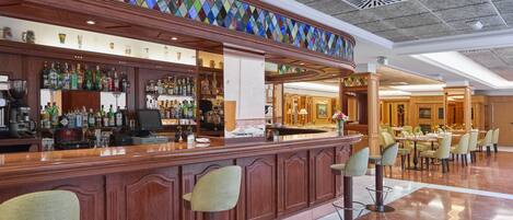 A bar area with a wooden counter, bar stools, and a variety of liquor bottles.