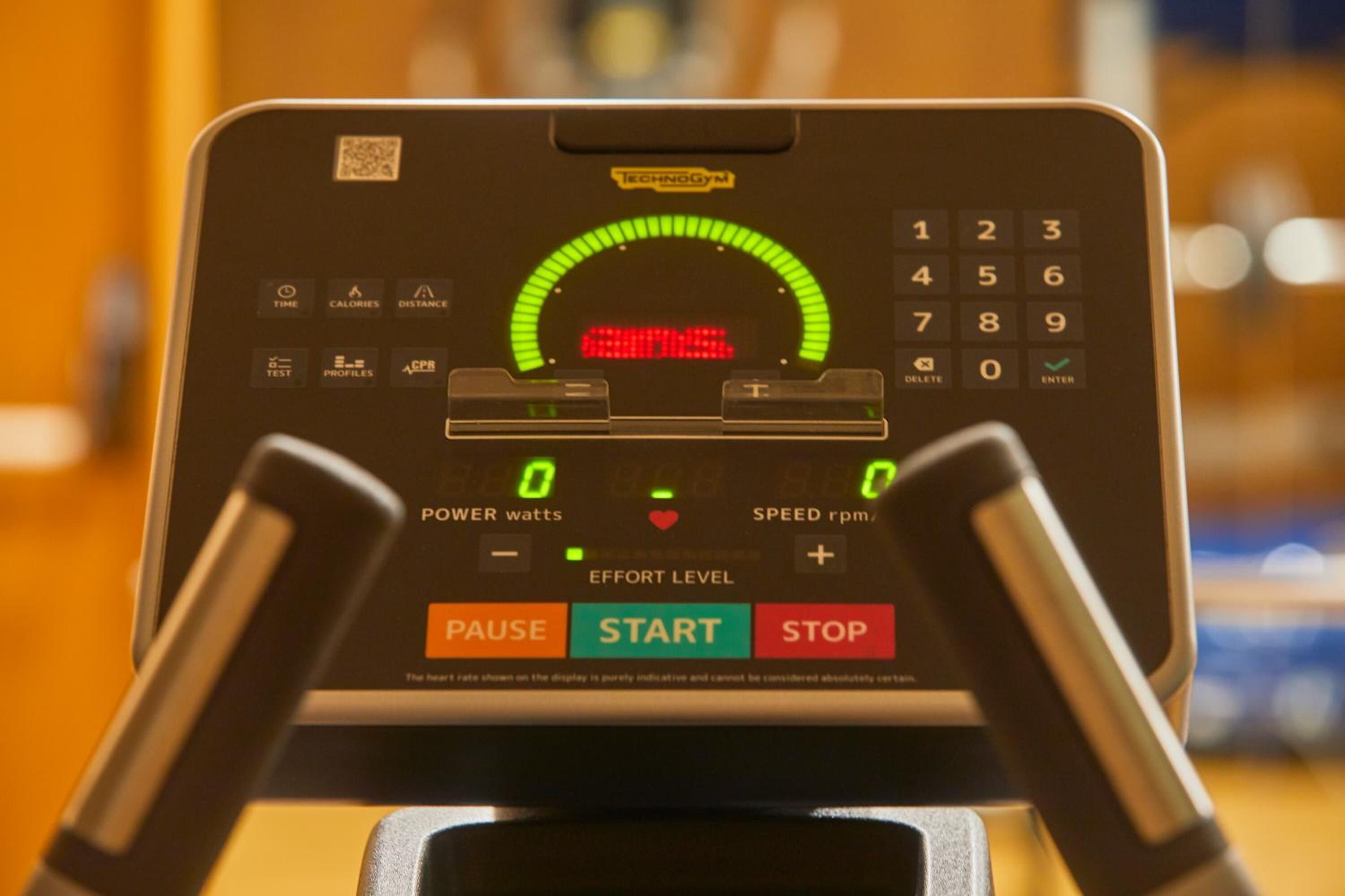 A treadmill control panel with a digital display, buttons for power, speed, and effort level, and a QR code.