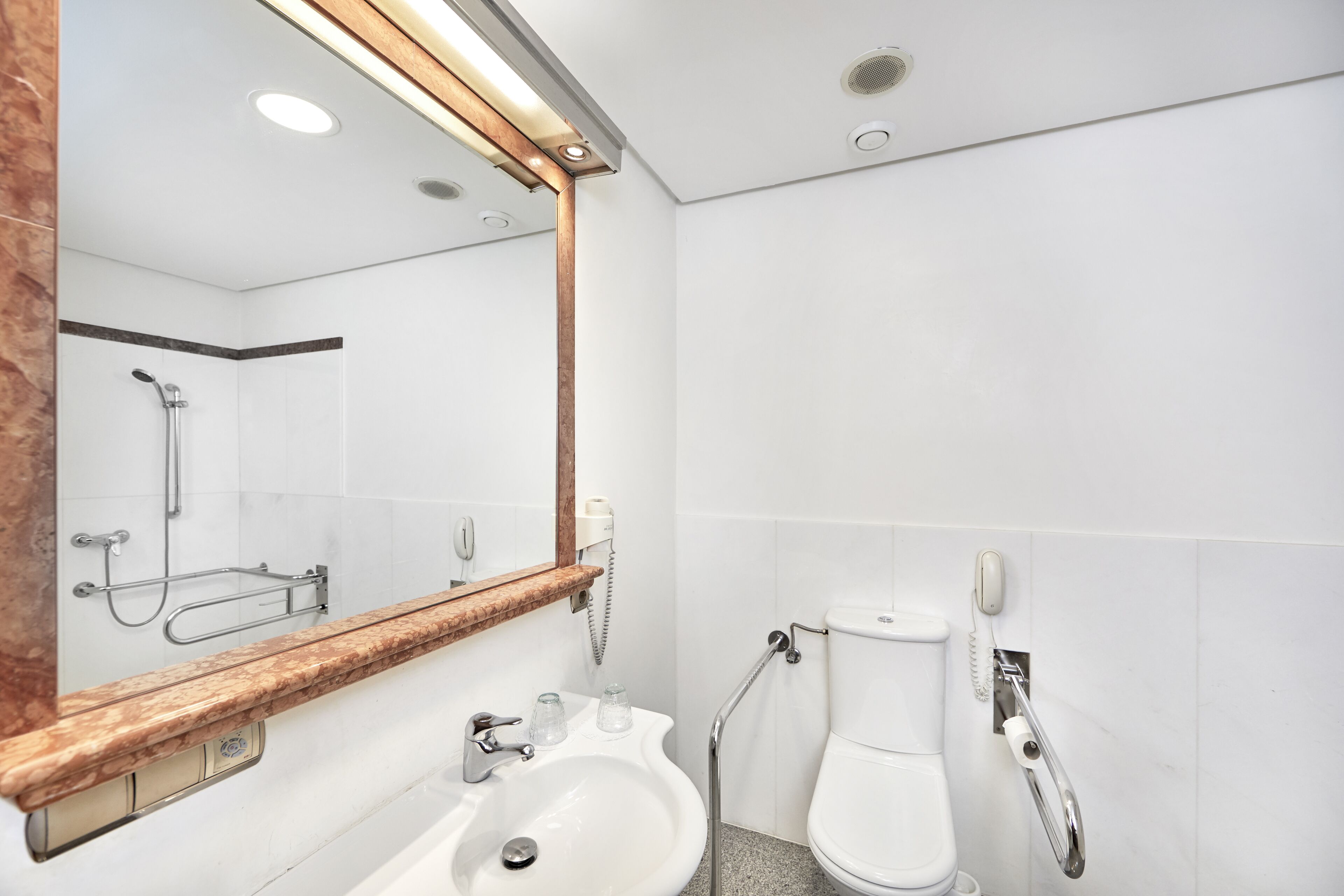 Un baño moderno con lavamanos, espejo y retrete.
