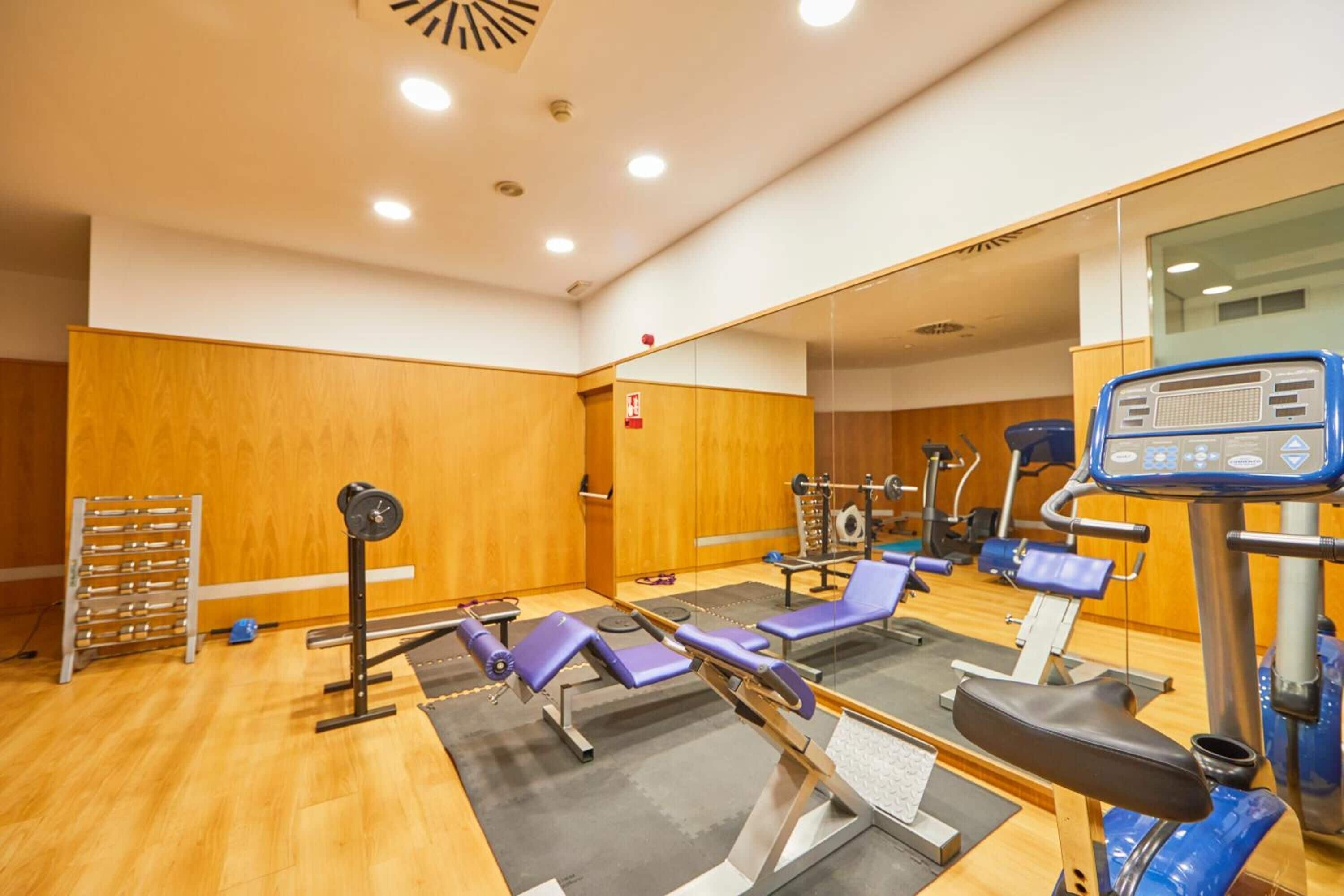 A gym with exercise equipment, including a treadmill, stationary bikes, and weight machines.