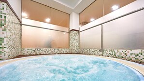 Un jacuzzi con revestimiento de azulejos y vistas al exterior a través de paneles de vidrio satinado.