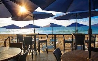 A beachside seating area with umbrellas and chairs facing the ocean.
