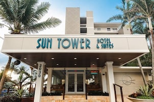 L’extérieur de l’hôtel Sun Tower Hotel & Suites se distingue par sa façade moderne, son entrée imposante avec des portes vitrées et un panneau indiquant les chambres disponibles.