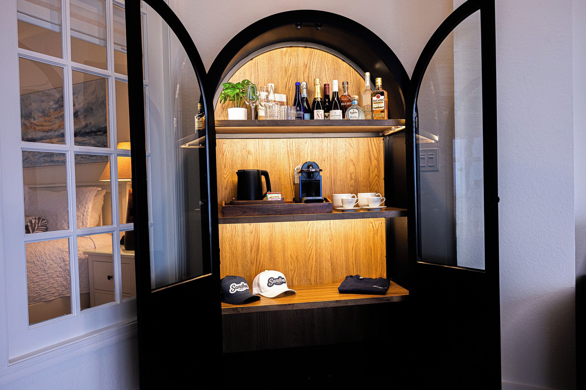 A compact bar area with a coffee machine, cups, and bottles of alcohol.